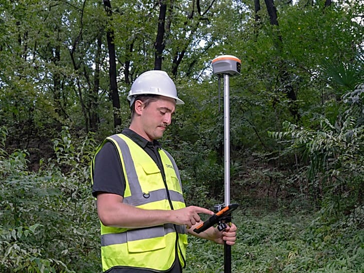 Surveyor using CHCNAV i85 GNSS receiver in the field for land surveying.